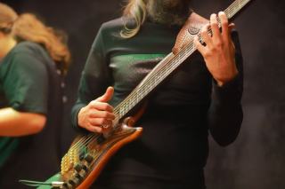Main droite d'un bassiste en position de slap au-dessus des dernières frettes