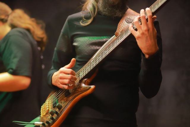 Main droite d'un bassiste en position de slap au-dessus des dernières frettes